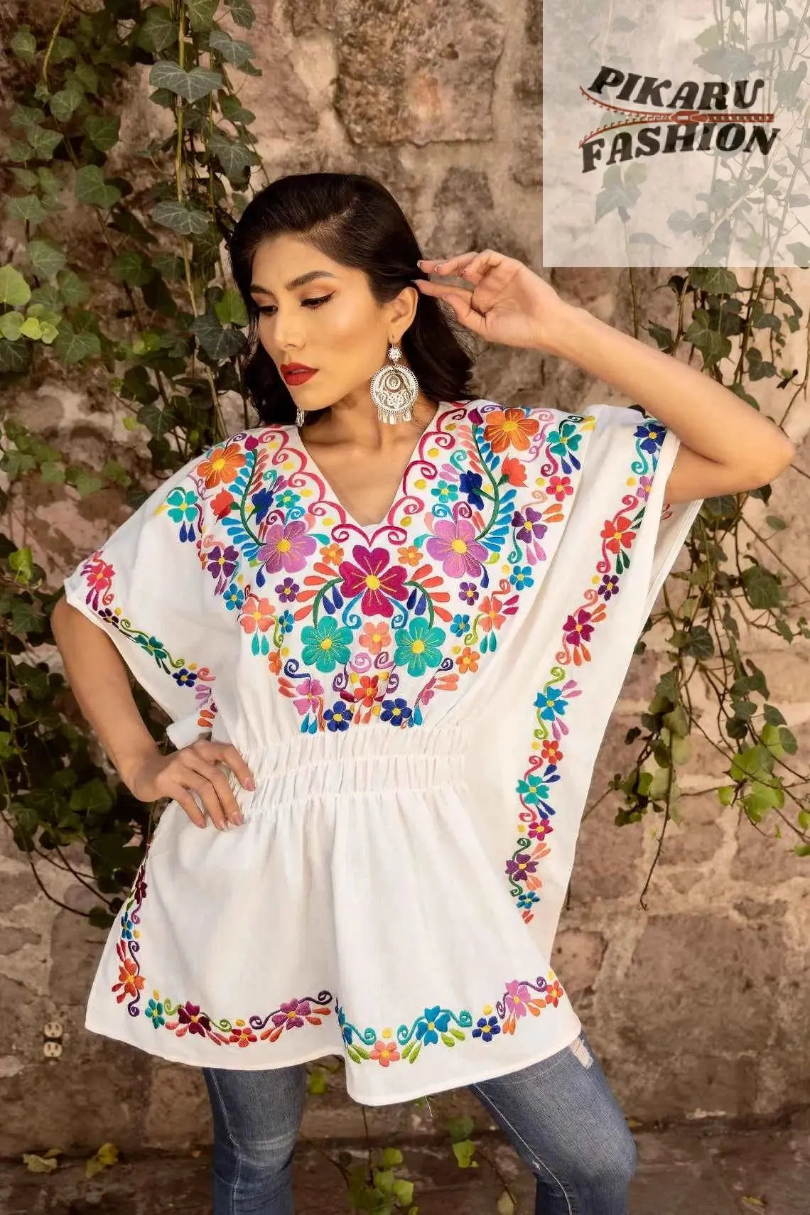 Mexican boho blouse featuring vibrant floral embroidery in bold colors on a model against a natural backdrop.