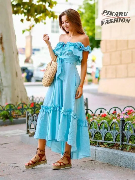 Woman in light blue off-shoulder maxi dress with ruffles, wearing sandals, outdoors