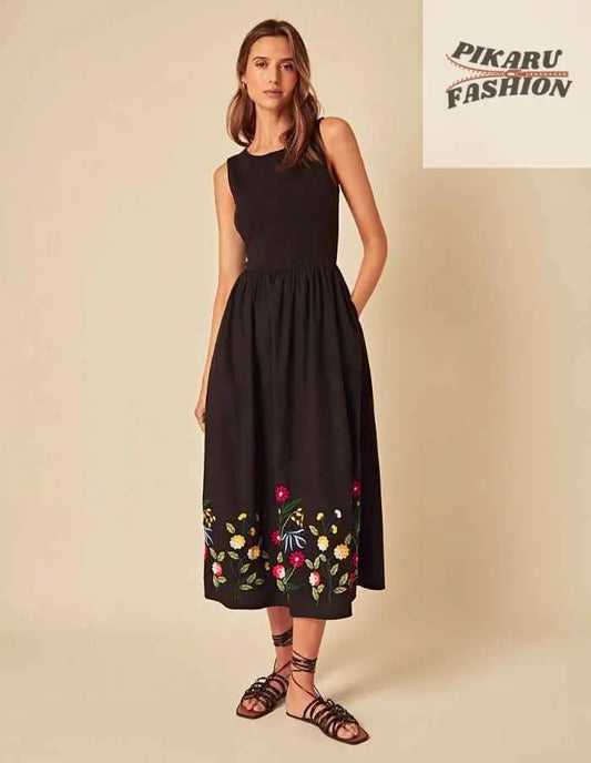 Woman wearing sleeveless black midi dress with colorful floral embroidery and sandals