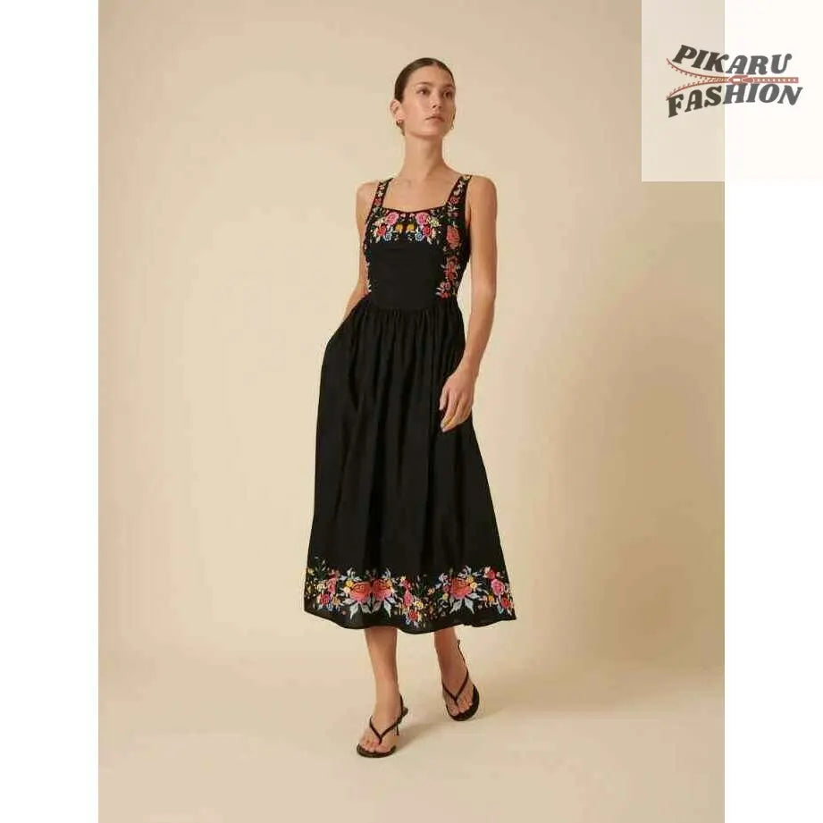Woman in black sleeveless floral embroidered midi dress with pockets and sandals