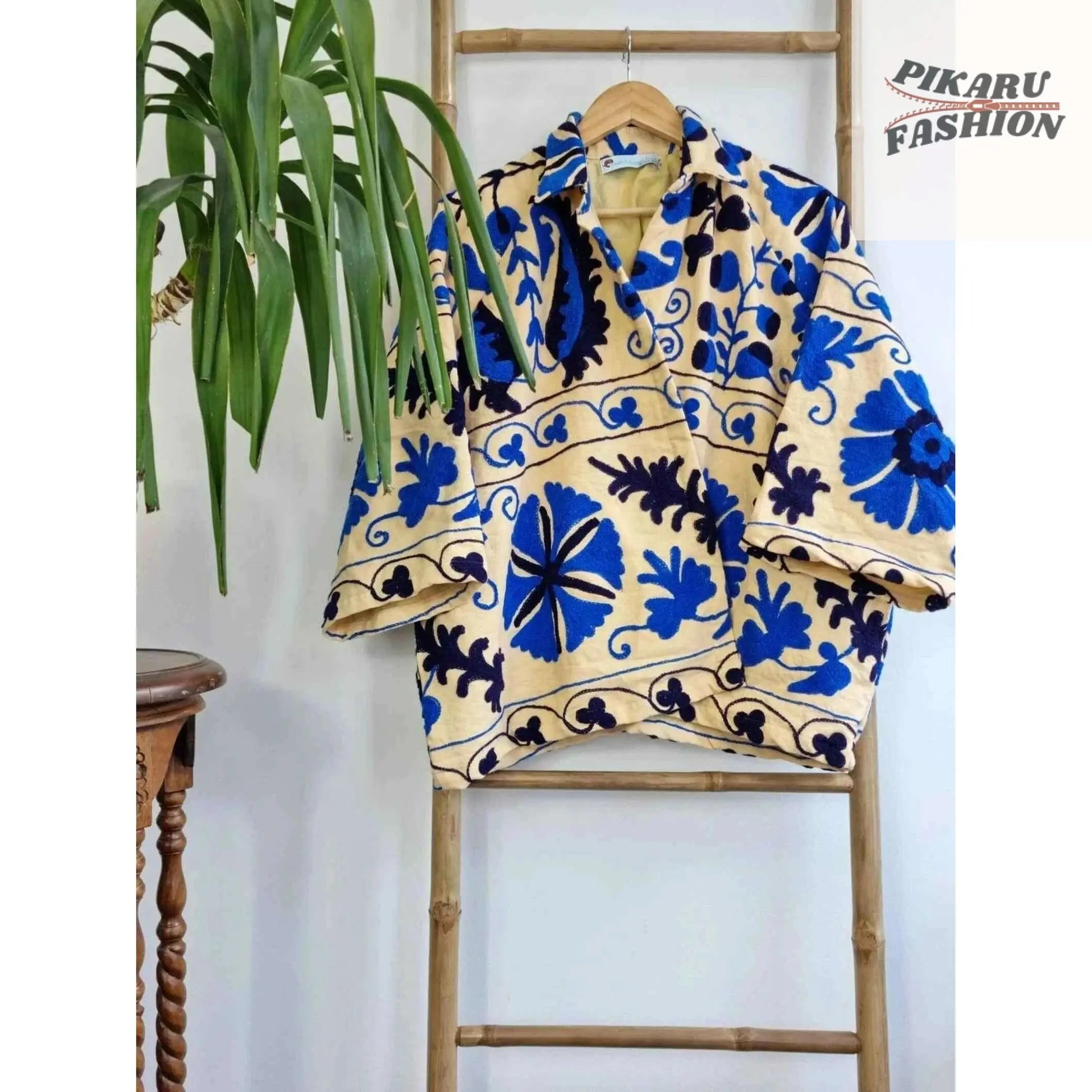 Blue Suzani embroidered jacket hanging on a wooden ladder indoors