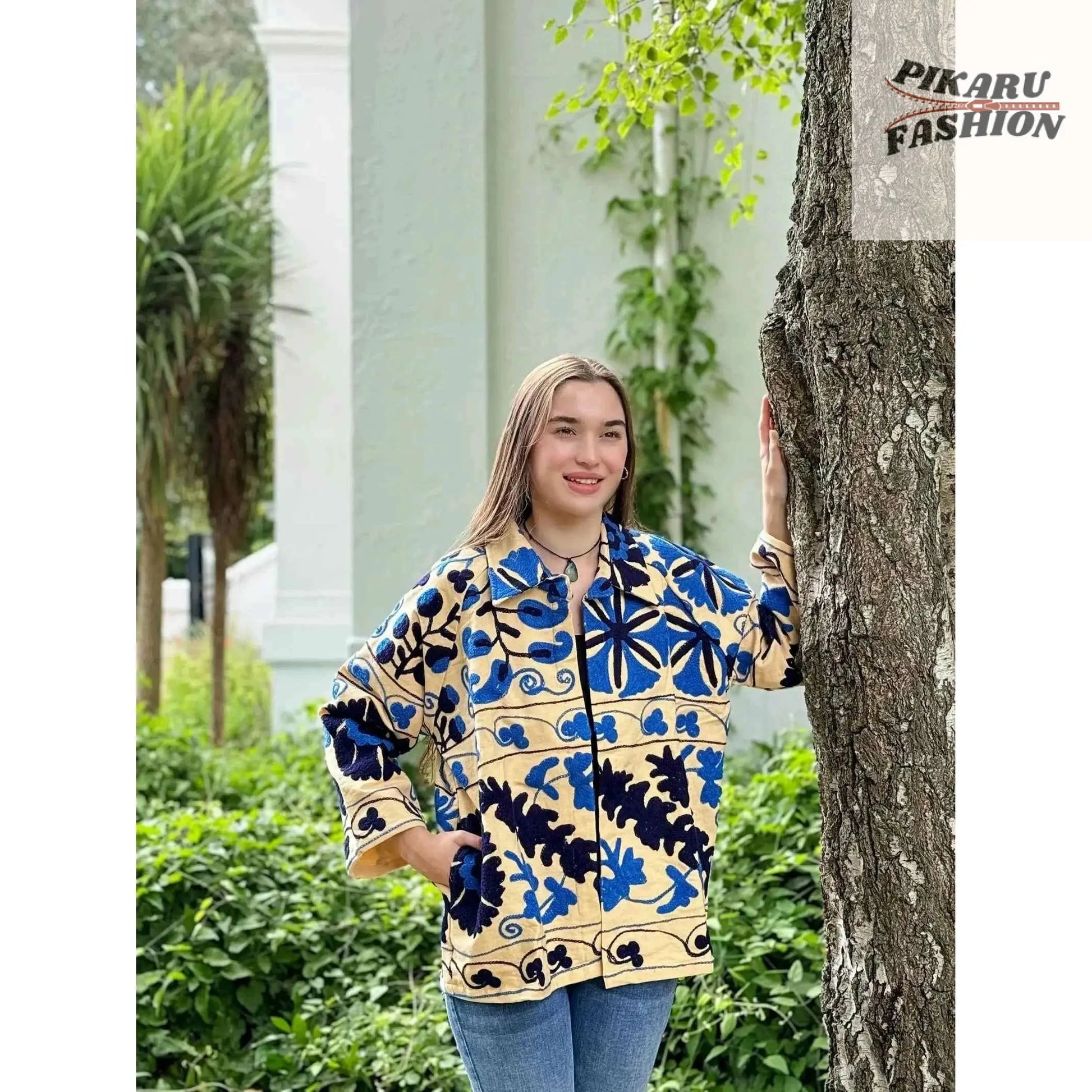 Model wearing a Blue Suzani embroidered jacket in an outdoor garden setting